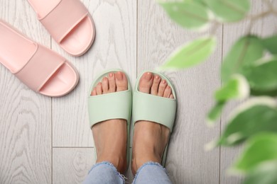 Photo of Woman wearing comfortable rubber slippers indoors, top view