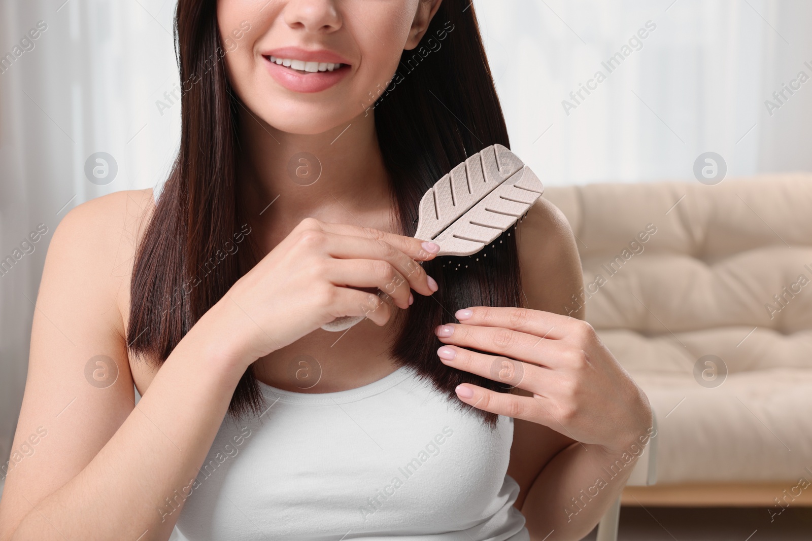 Photo of Woman brushing her hair near mirror in room, closeup. Space for text