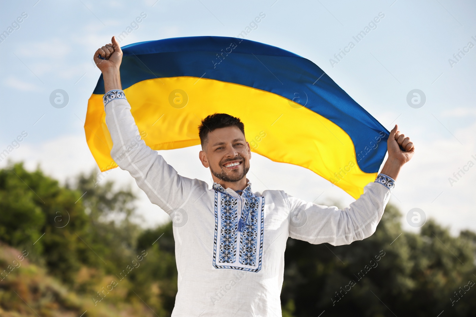 Photo of Man in vyshyvanka with flag of Ukraine outdoors