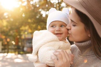 Photo of Happy mother with her baby daughter outdoors on autumn day, space for text