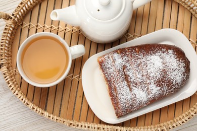 Delicious yeast dough cake and tea on wicker tray, top view