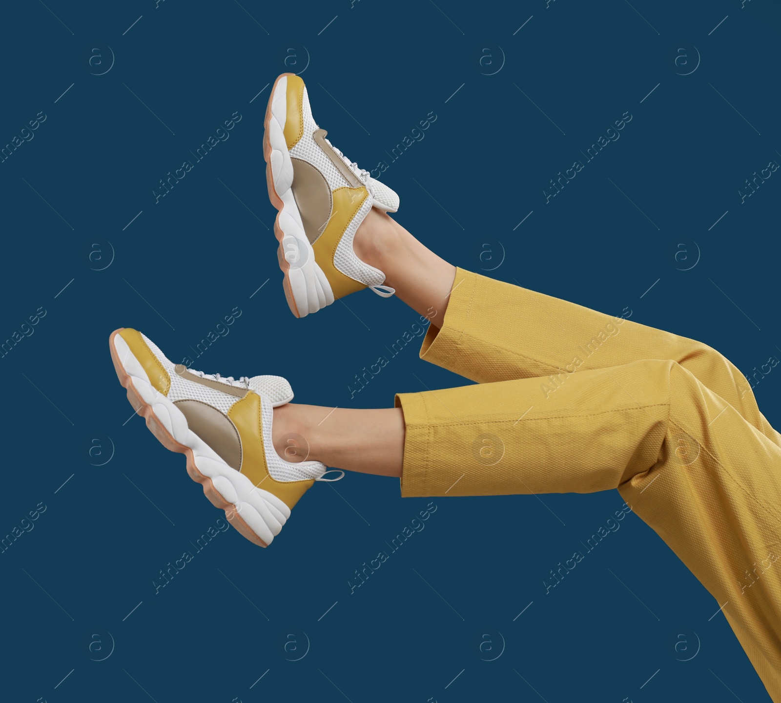 Photo of Woman in stylish sport shoes on blue background