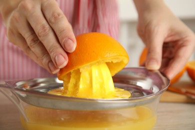 Woman squeezing orange juice at table, closeup