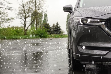 Image of Modern car parked outdoors on rainy day with hail