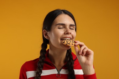 Photo of Young woman with chocolate chip cookie on orange background