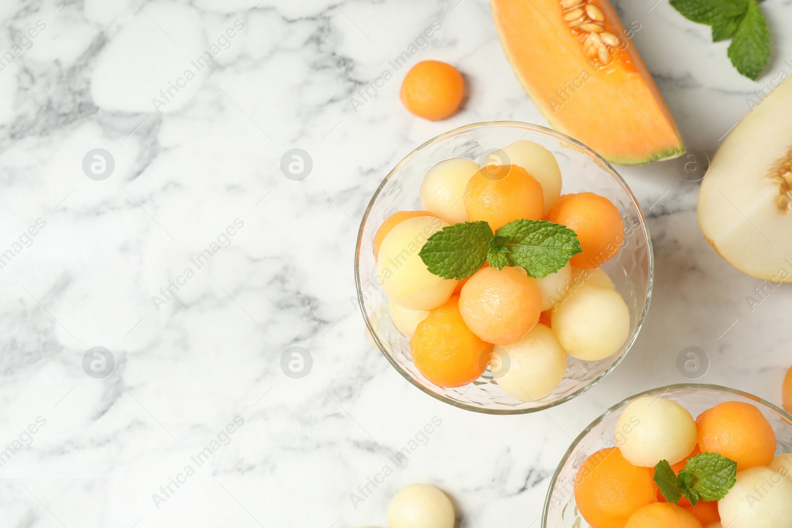 Photo of Flat lay composition with melon balls and mint on white marble table, space for text