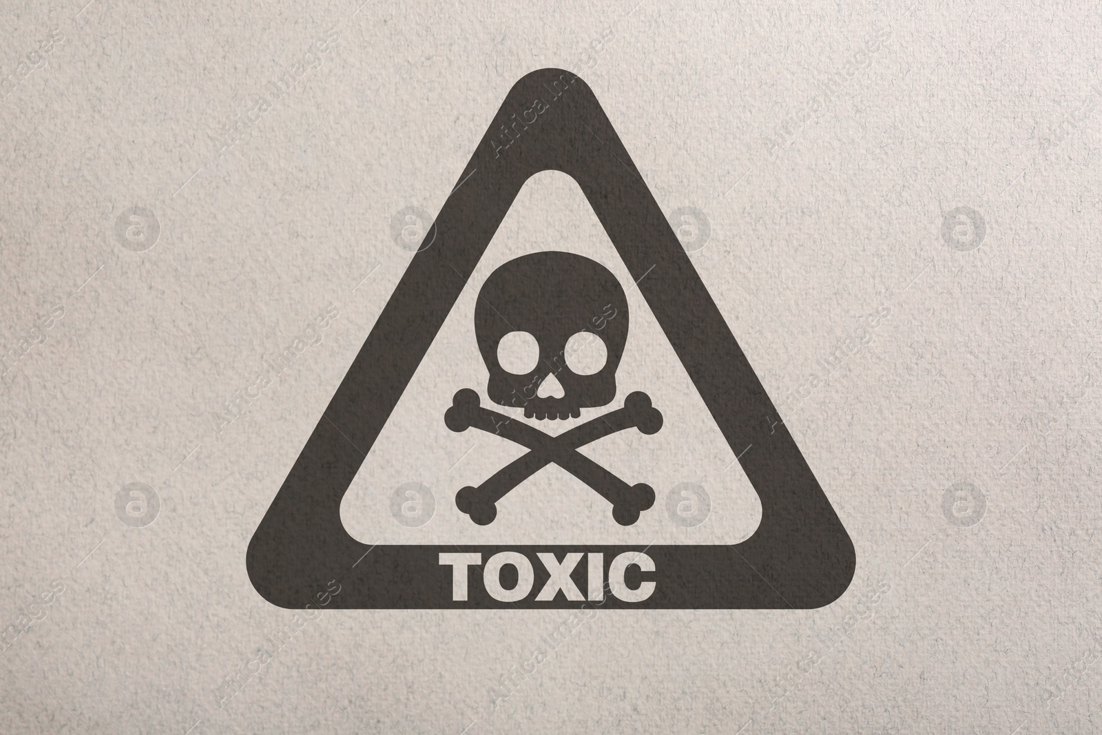 Image of Hazard warning sign (skull-and-crossbones symbol and word TOXIC) on paper, top view