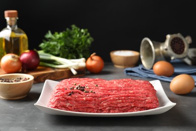 Photo of Raw ground meat and different products on grey table