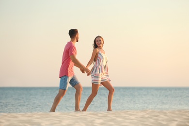 Happy young couple walking together on beach