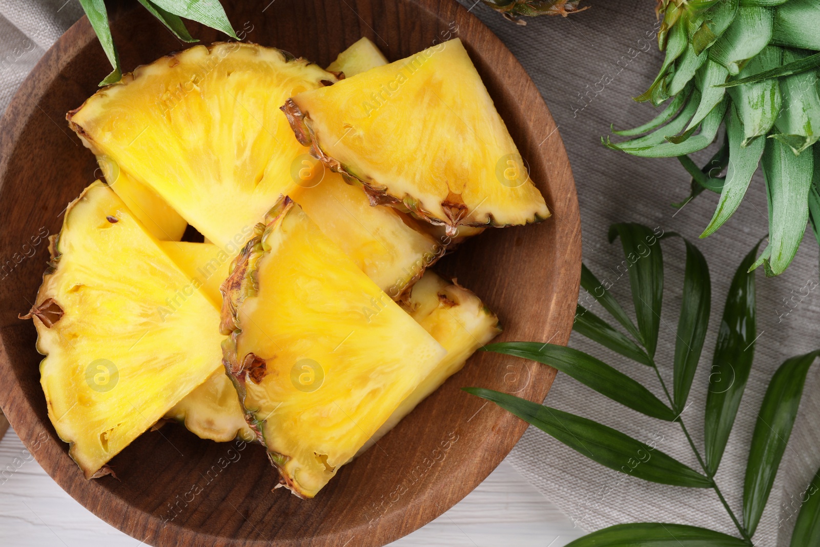 Photo of Pieces of tasty ripe pineapple on white wooden table, flat lay