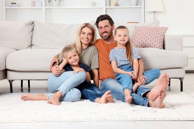 Portrait of happy family with children on soft rug at home
