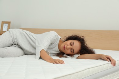 Photo of Young African American woman sleeping on bed with comfortable mattress at home