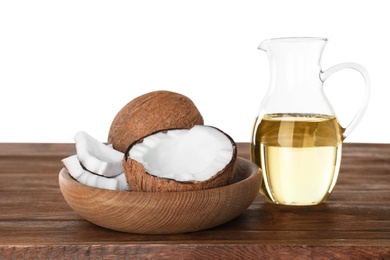 Photo of Composition with natural organic oil and ripe coconuts on wooden table against white background