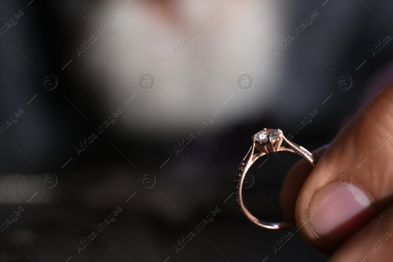 Photo of Male jeweler holding diamond ring, closeup view. Space for text