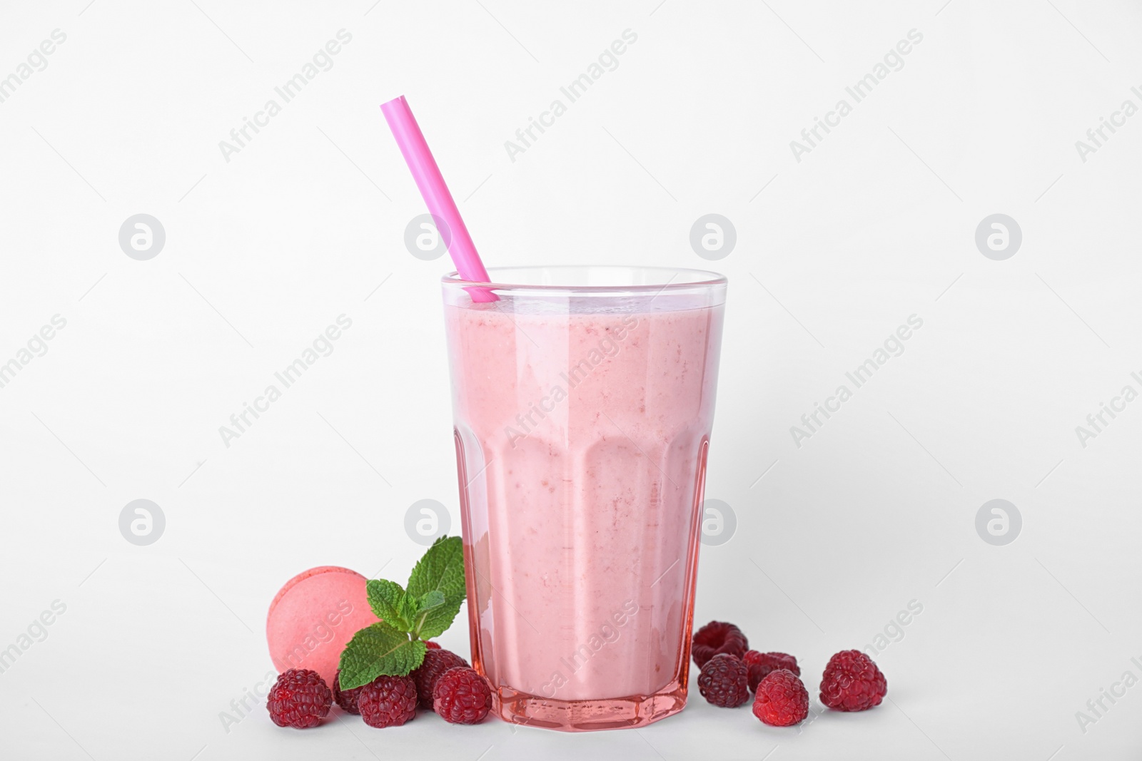 Photo of Tasty milk shake in glass, raspberries and macaron on white background