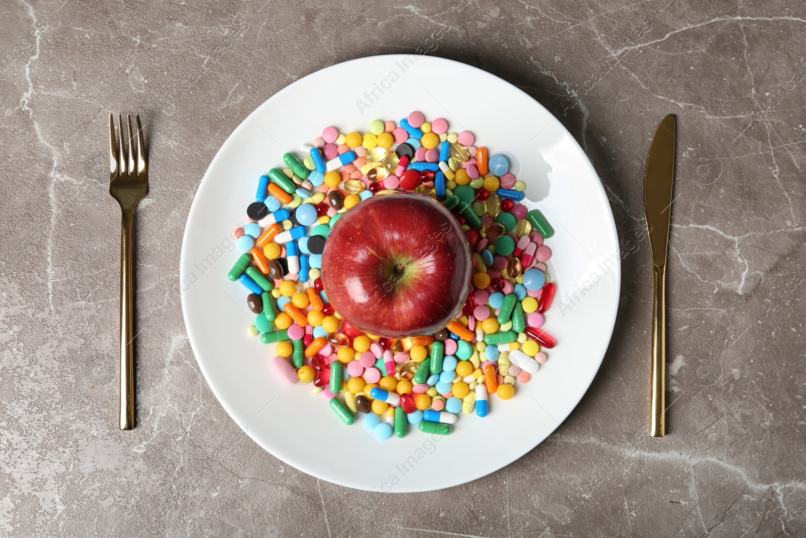 Photo of Plate with weight loss pills and apple near cutlery on gray background, flat lay