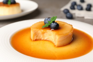 Photo of Delicious pudding with caramel and blueberries on plate, closeup