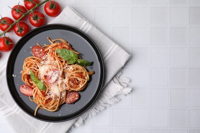 Tasty pasta with tomato sauce, cheese and basil on white tiled table, flat lay. Space for text