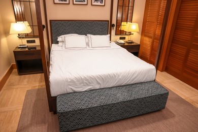 Large bed between bedside tables with lamps in comfortable hotel room