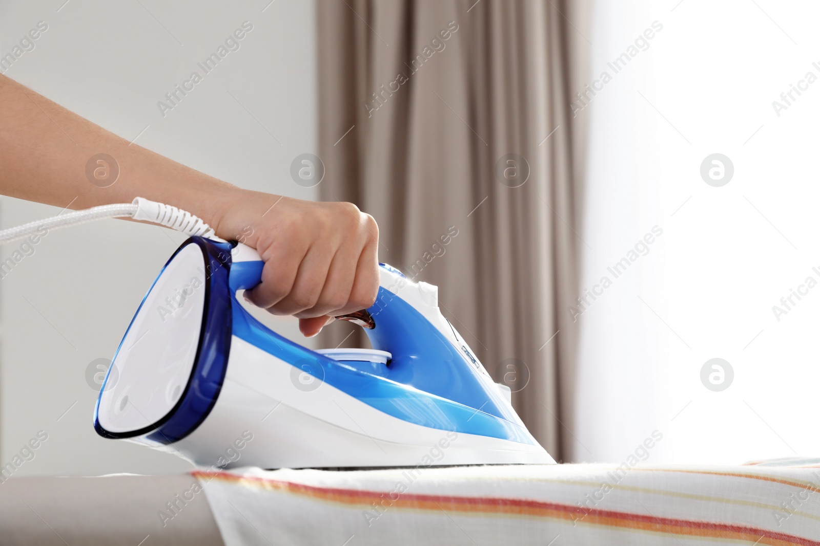 Photo of Woman ironing clothes on board indoors, space for text. Household chores