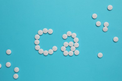 Photo of Flat lay composition with calcium supplement pills on light blue background