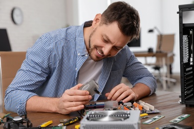 Male technician repairing motherboard at table indoors