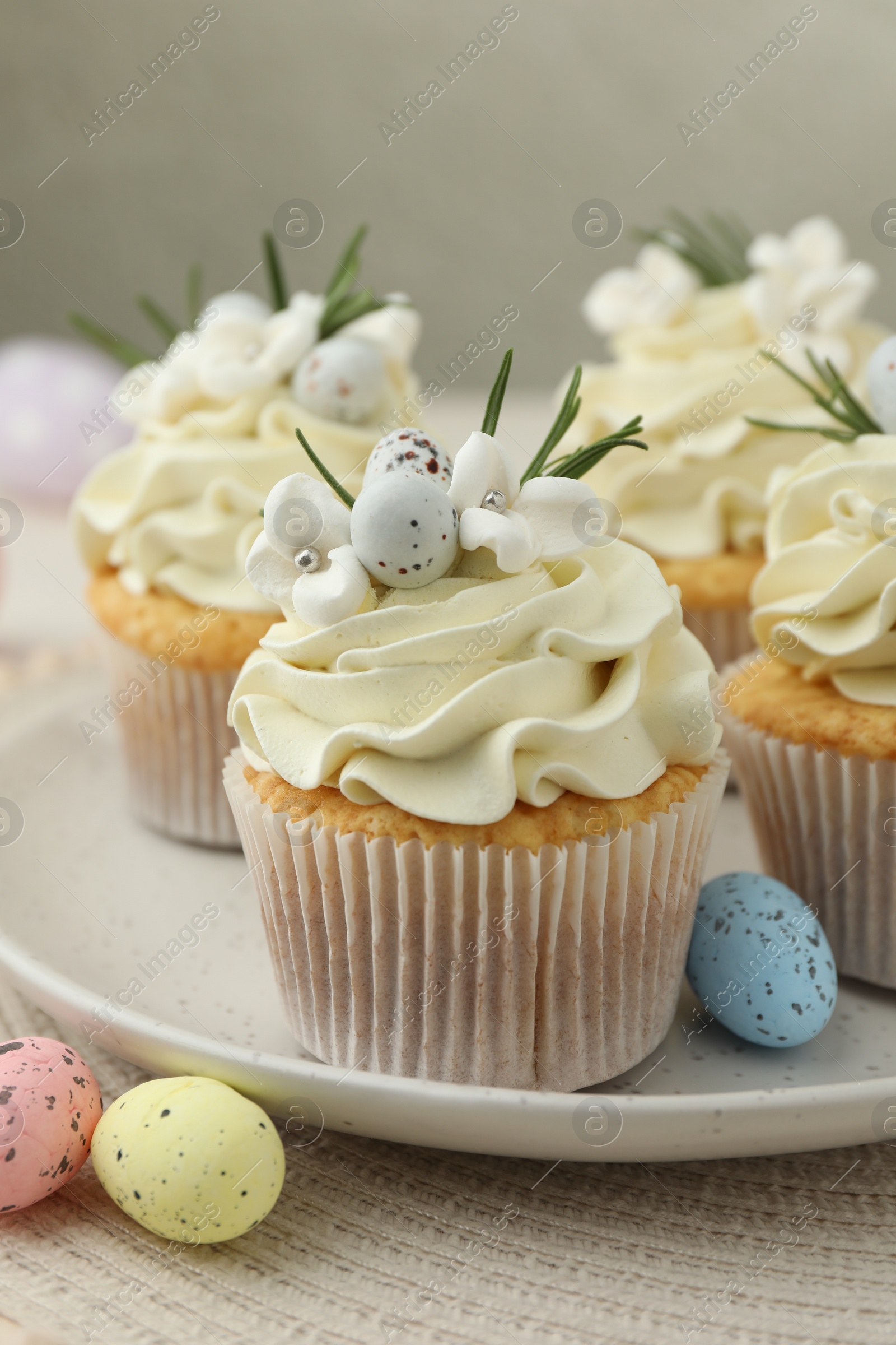 Photo of Tasty Easter cupcakes with vanilla cream and candies on table, closeup