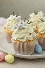 Tasty Easter cupcakes with vanilla cream and candies on table, closeup