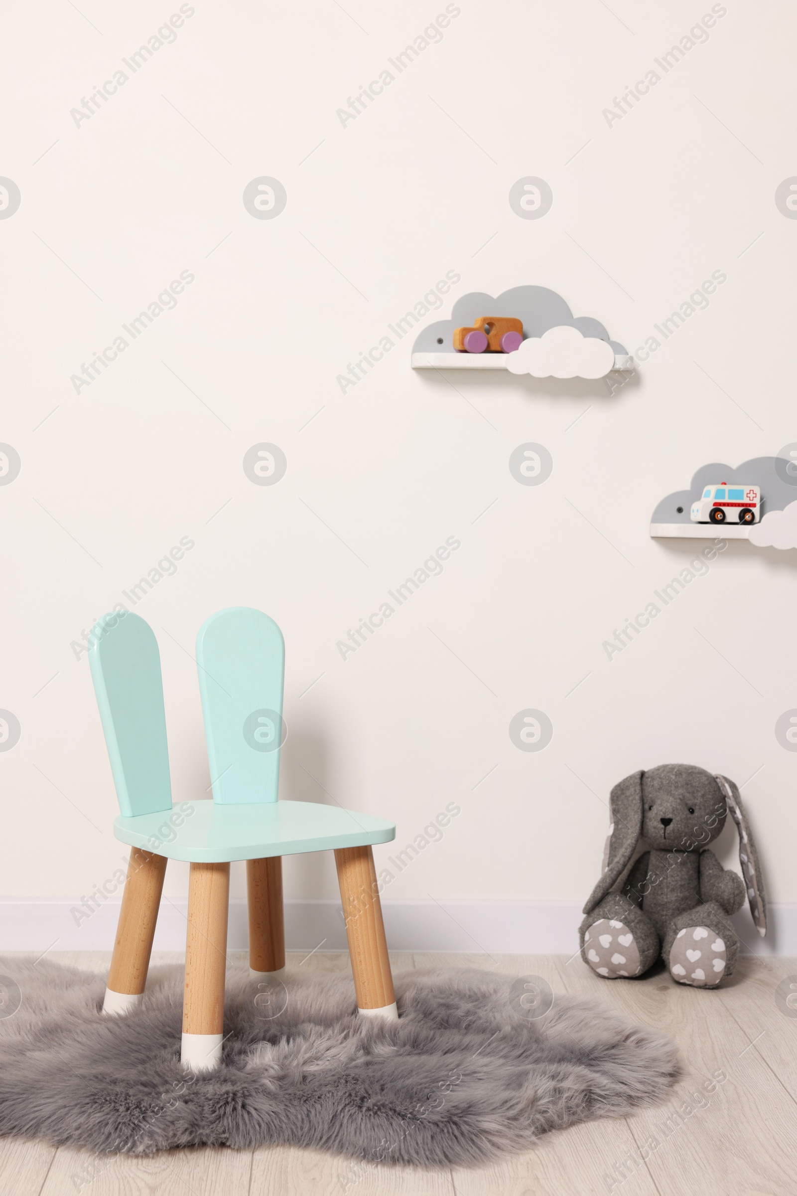 Photo of Beautiful children's room with light wall, chair and toys. Interior design