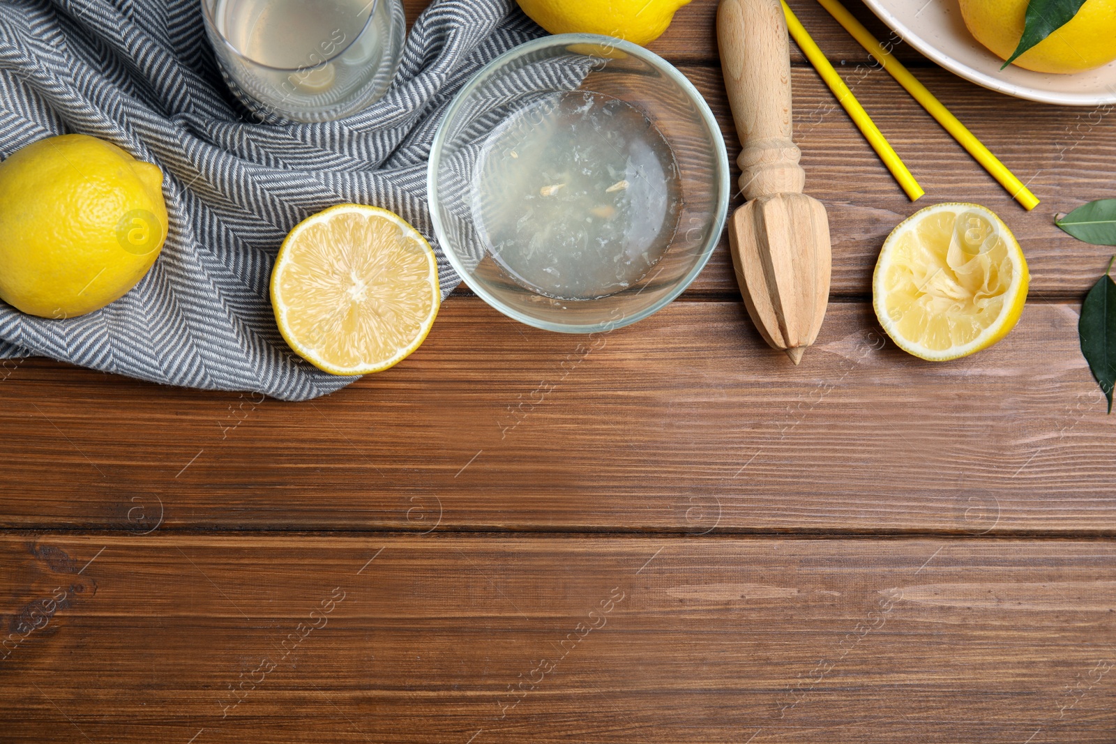 Photo of Citrus reamer, juice and fresh lemons on wooden table, flat lay. Space for text