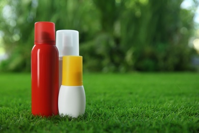 Different insect repellents on green grass. Space for text