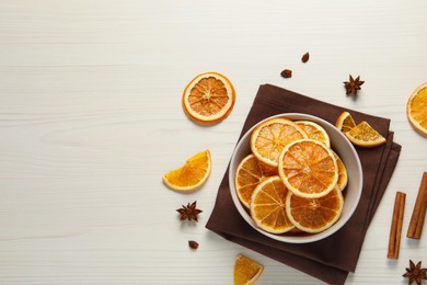 Many dry orange slices and spices on white wooden table, flat lay. Space for text