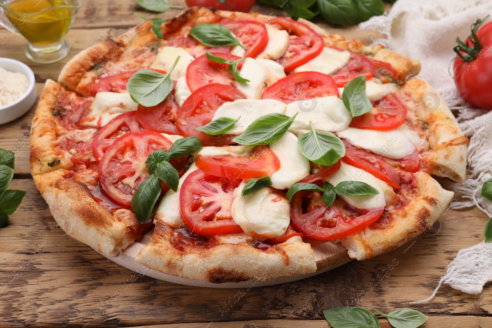 Photo of Delicious Caprese pizza with tomatoes, mozzarella and basil on wooden table, closeup