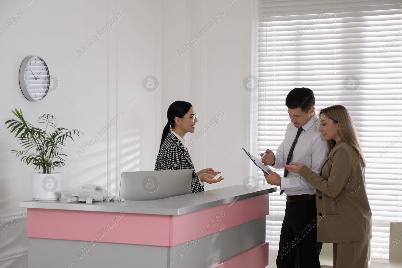 Photo of Receptionist working with clients at countertop in office