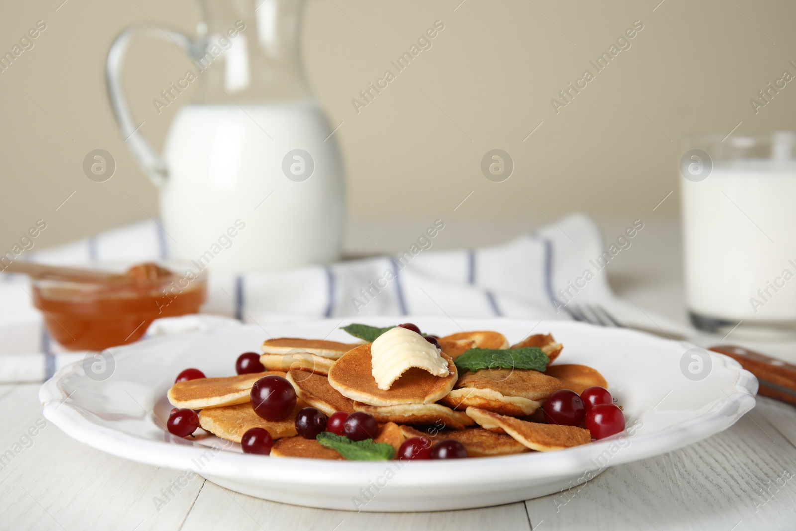 Photo of Cereal pancakes with cranberries and butter on white wooden table