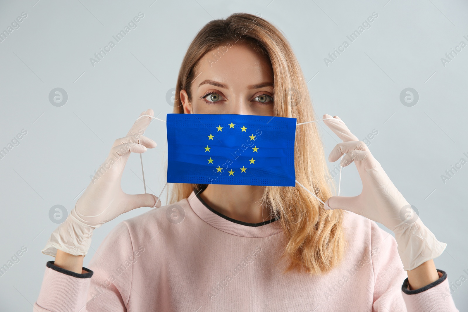 Image of Woman wearing medical mask with European Union flag on light background. Coronavirus outbreak in Europe