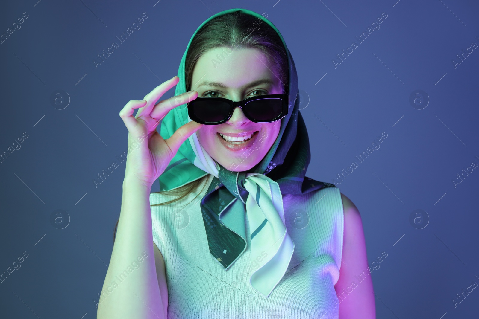 Photo of Portrait of beautiful young woman with sunglasses on color background with neon lights