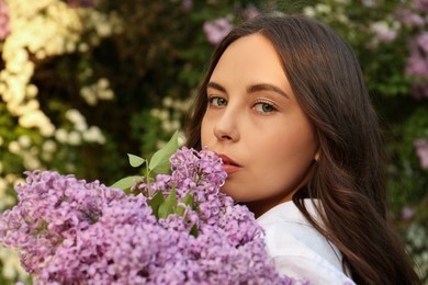 Photo of Attractive young woman with lilac flowers outdoors