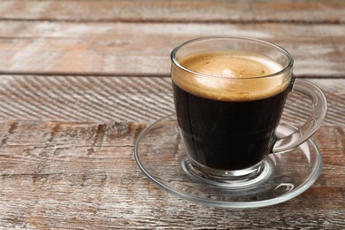 Photo of Cup of aromatic coffee on wooden table, closeup. Space for text