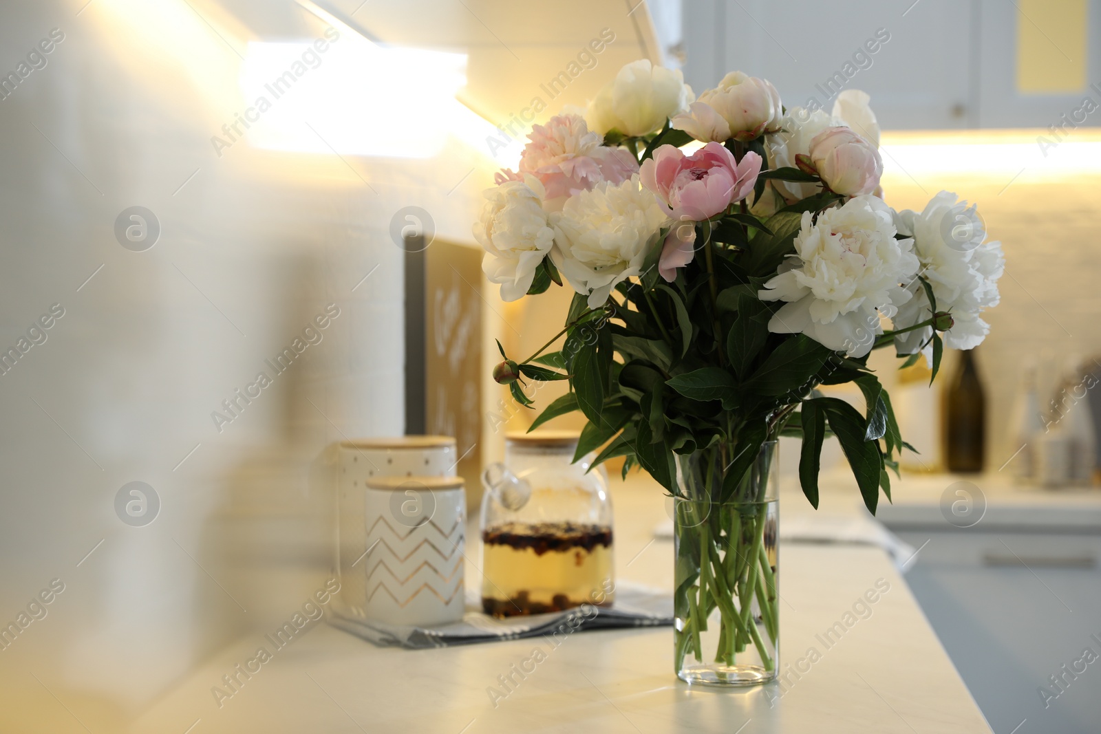 Photo of Beautiful peonies in vase on kitchen counter