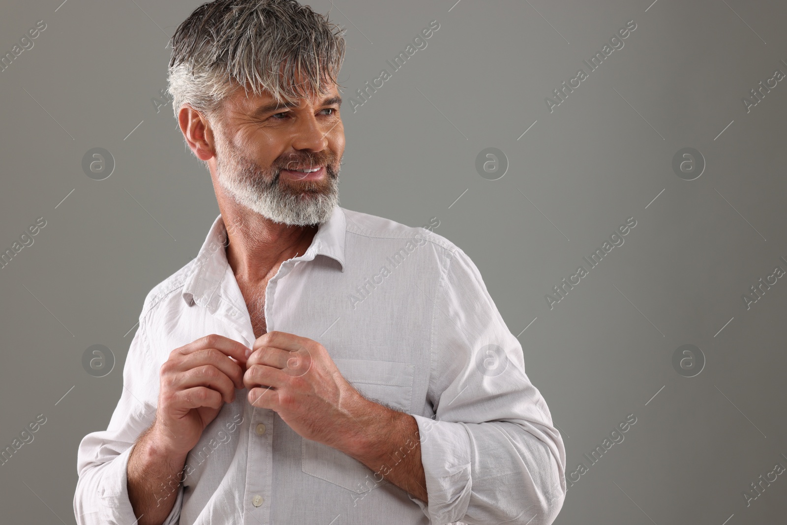 Photo of Portrait of smiling man with beautiful hairstyle on light grey background. Space for text