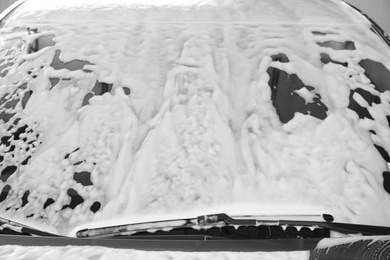 Automobile covered with foam at car wash, closeup of windshield
