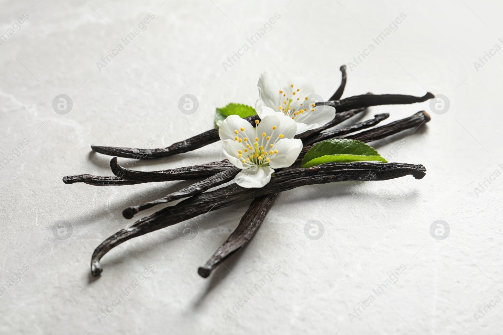 Photo of Vanilla sticks and flowers on light background