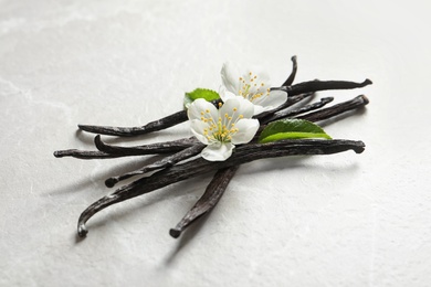 Vanilla sticks and flowers on light background