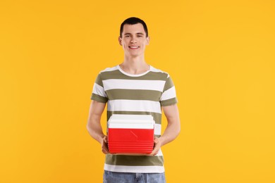 Man with red cool box on orange background