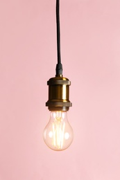 Photo of Hanging modern lamp bulb against pink background