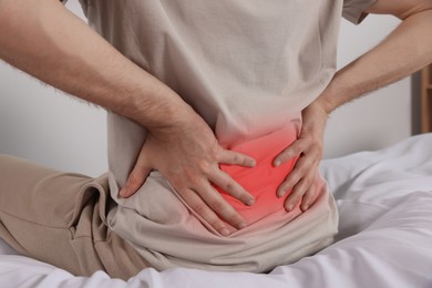 Man suffering from pain in lower back indoors, closeup