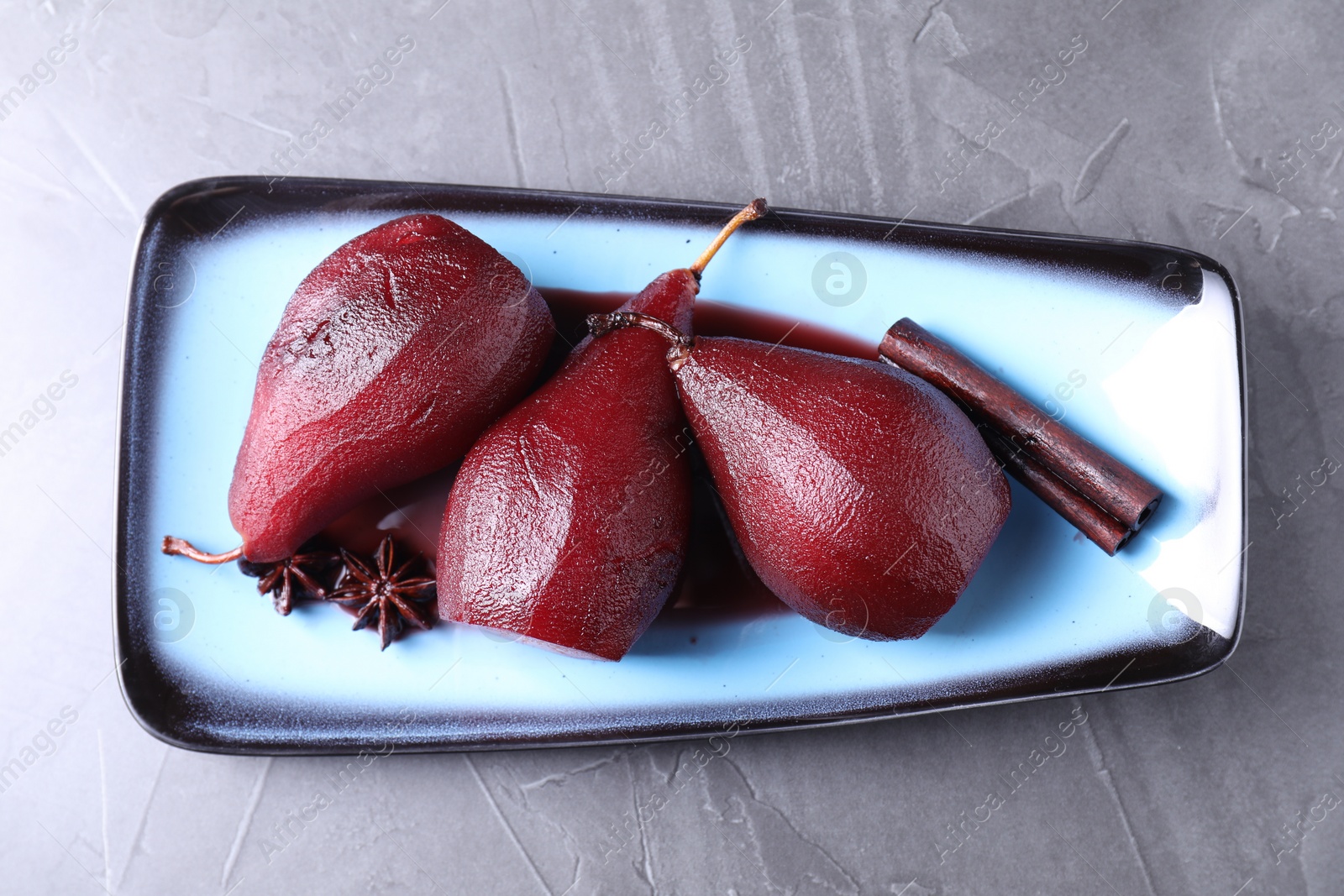 Photo of Tasty red wine poached pears and spices on grey table, top view