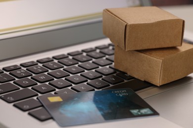 Photo of Mini boxes and credit card on laptop, closeup. Online store