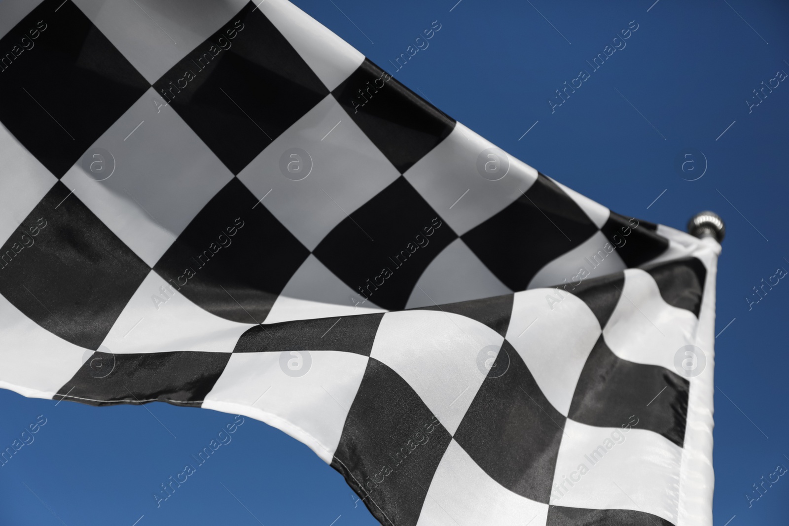 Photo of Checkered finish flag on blue background, closeup